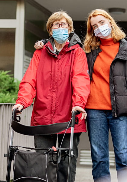 Mobile Mental Health - mom and daughter at retirement home looking happy and staying safe with masks