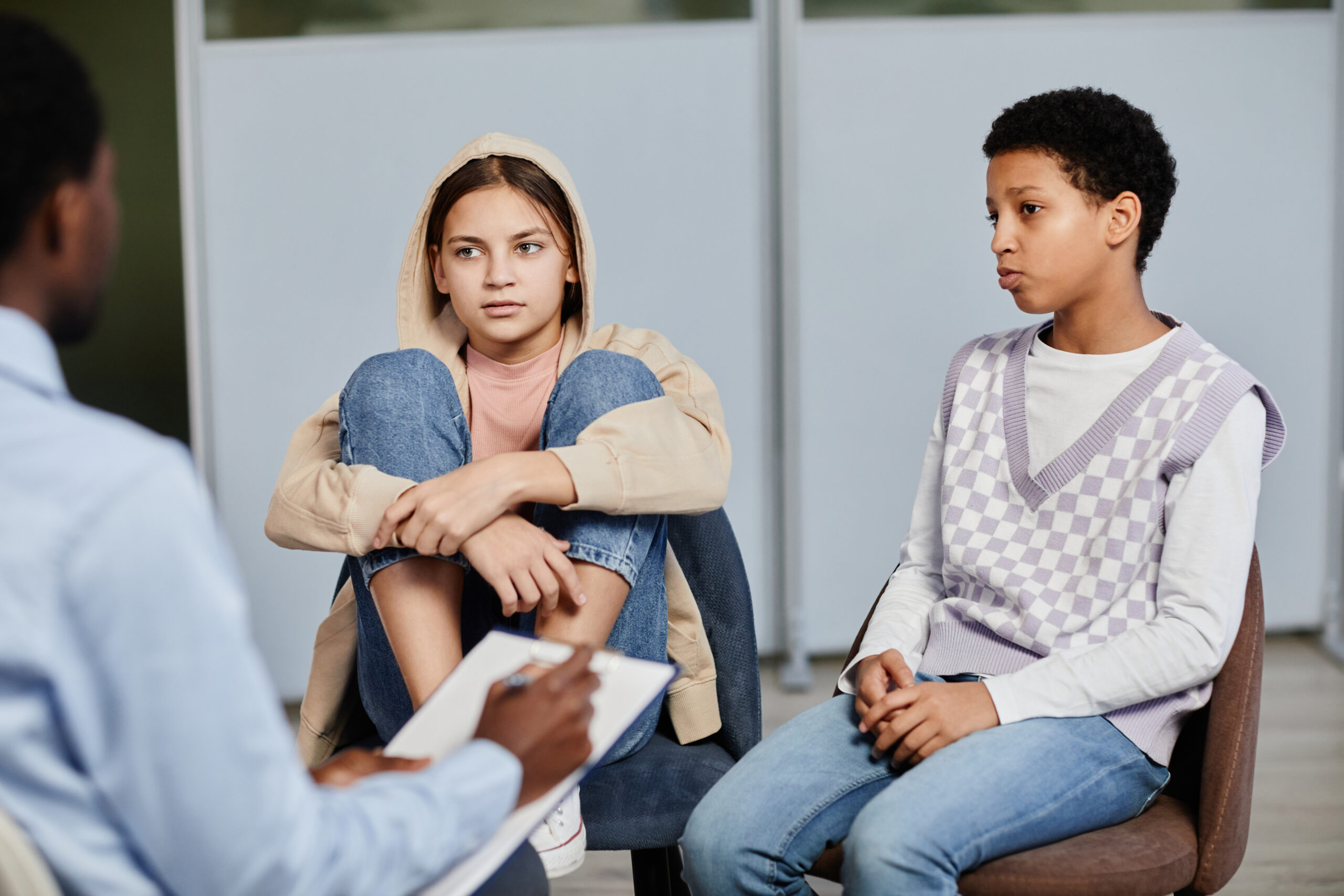 Portrait of two teenage girls speaking to psychologist in therapy session