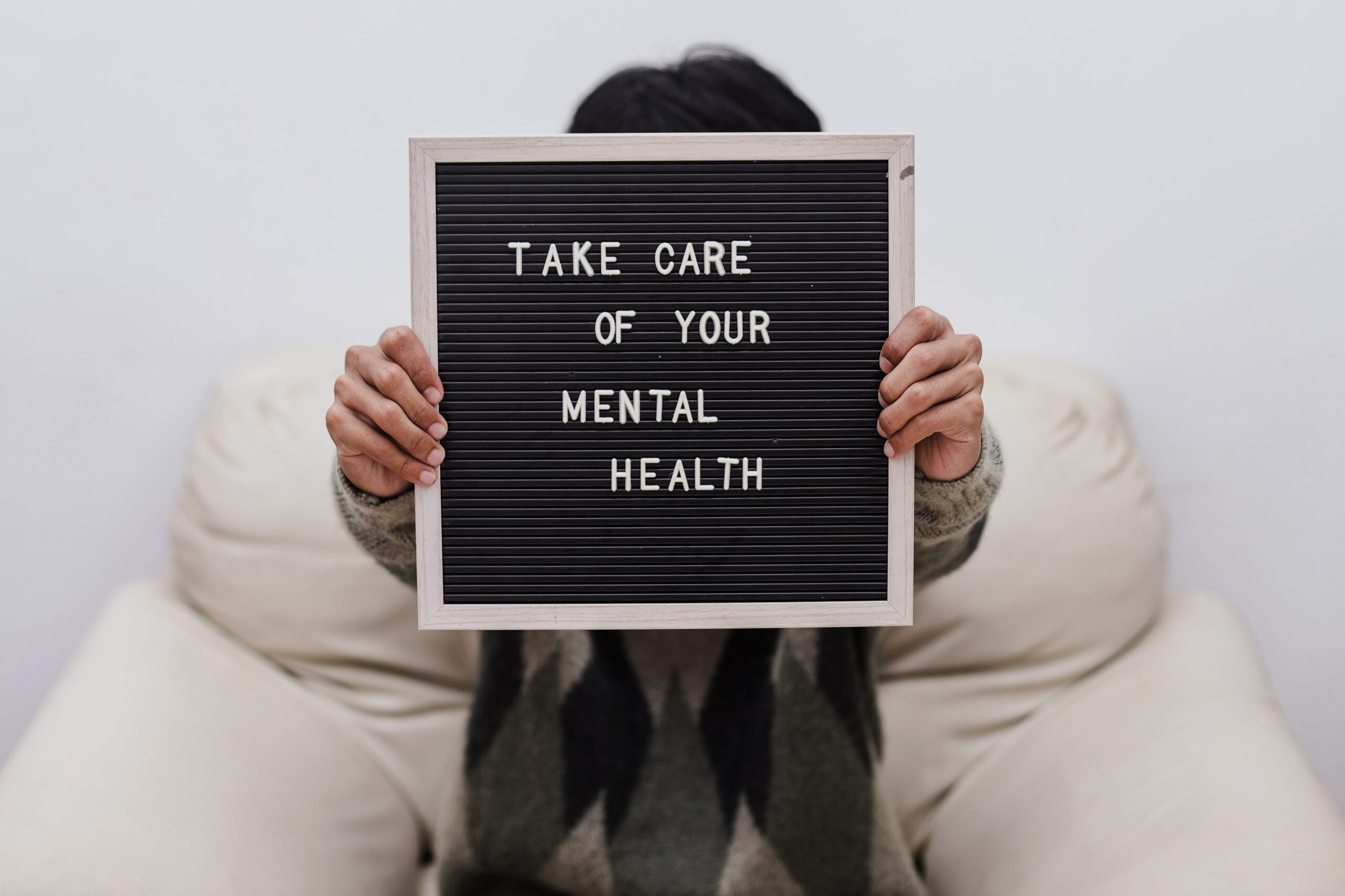 person holding up a sign that says take care of your mental health