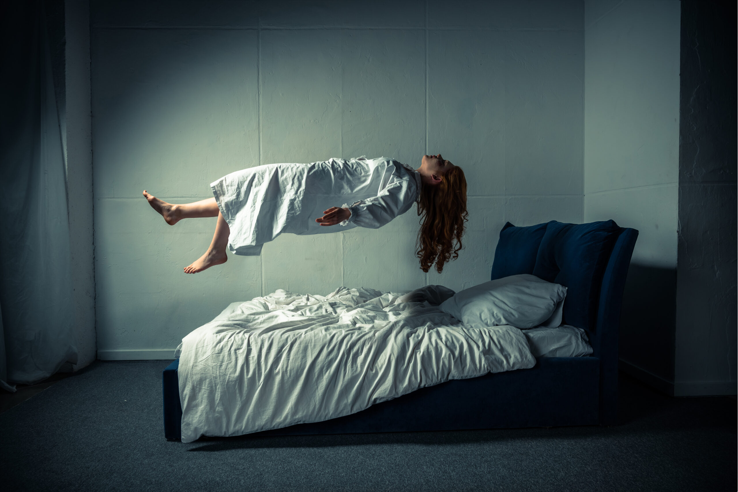 girl in nightgown levitating over bed