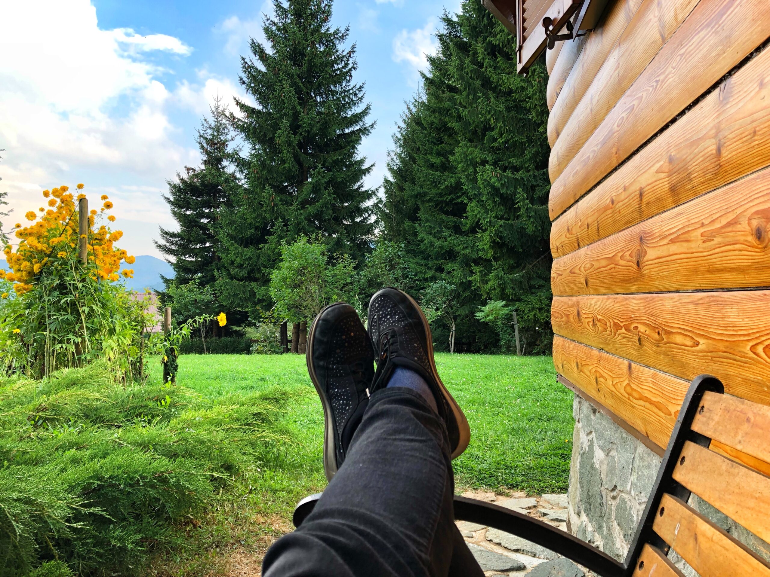 man sitting outside on a summer day relaxing with his feet up