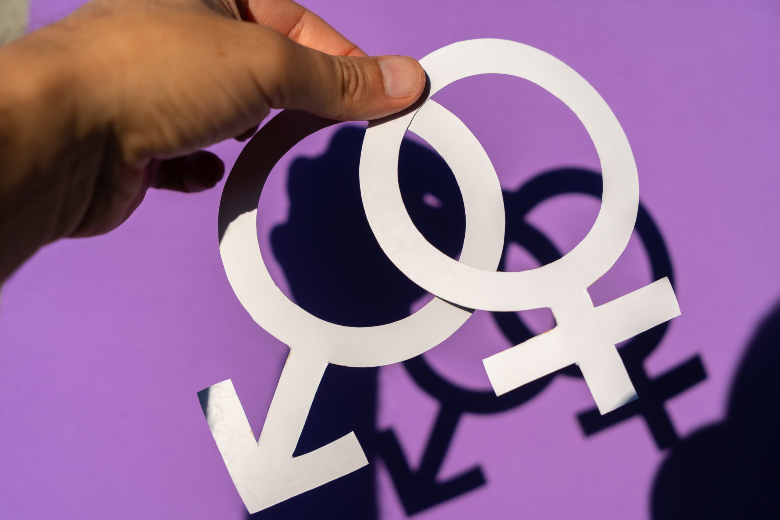 A man holding the male and female symbol on a purple background, gender equality and fighting for women's rights and equality