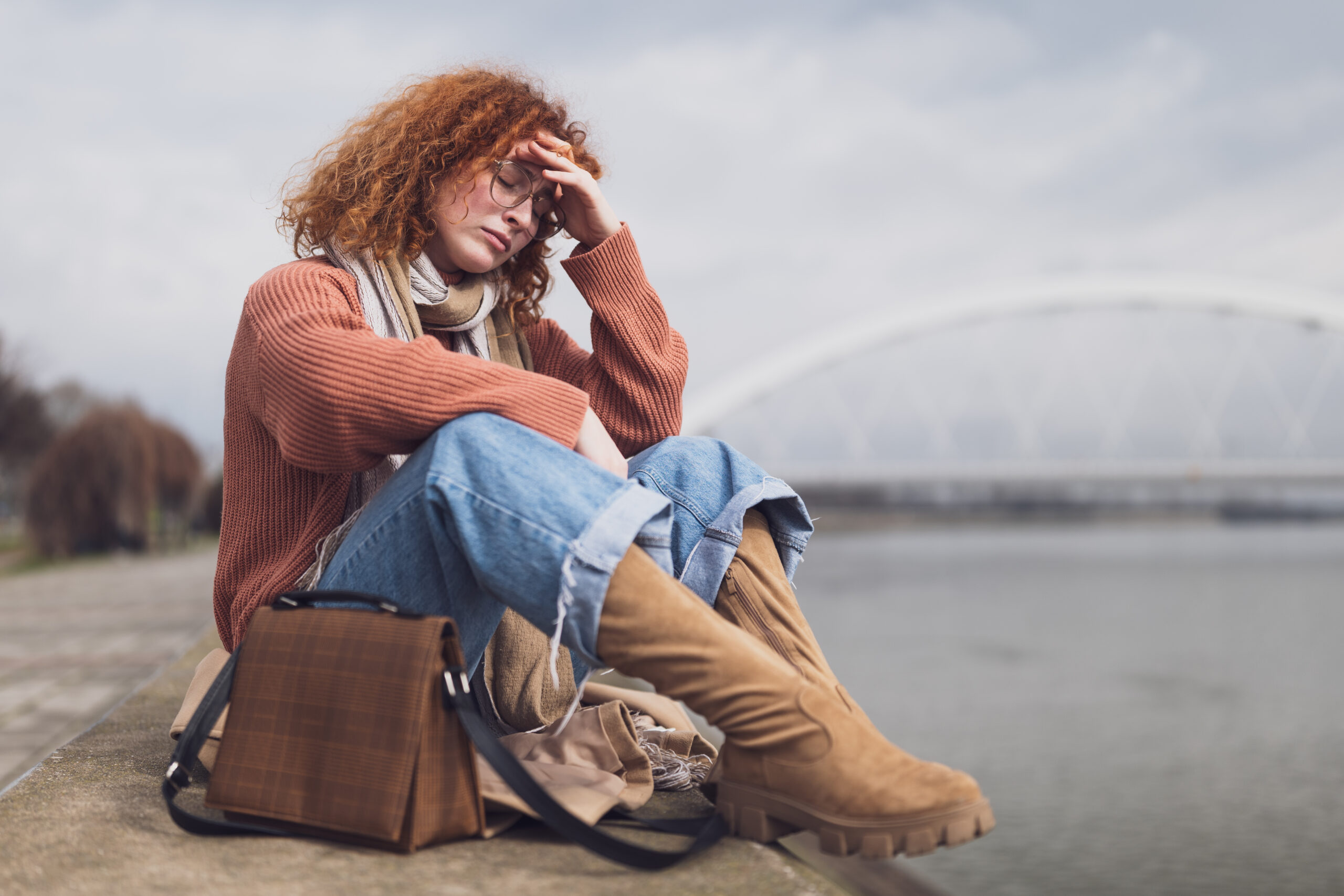 woman suffering with anhedonia and sitting at the beach miserable