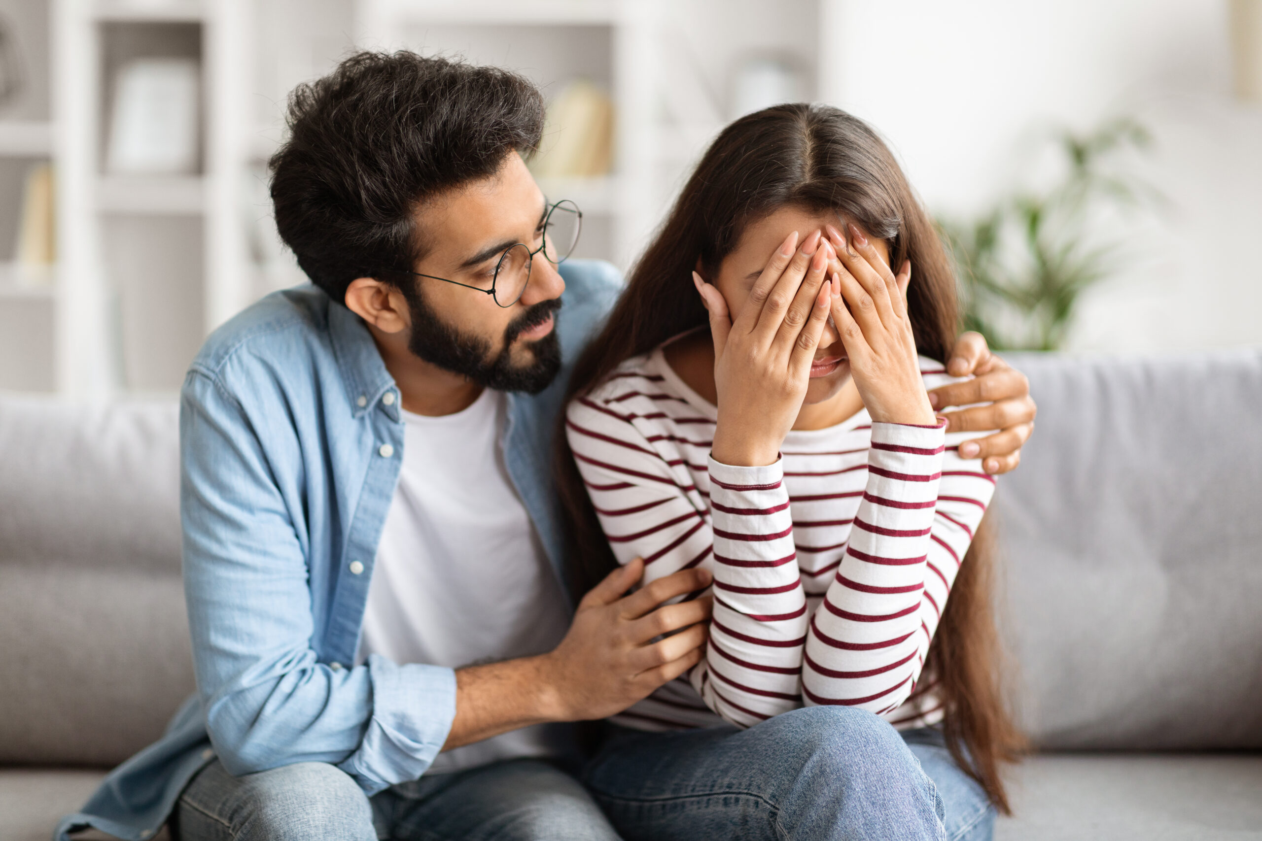 Loving husband indian man comforting consoling upset crying wife woman, giving psychological support care compassion, helping sharing grief or problem, miscarriage, empathy in couple relationships