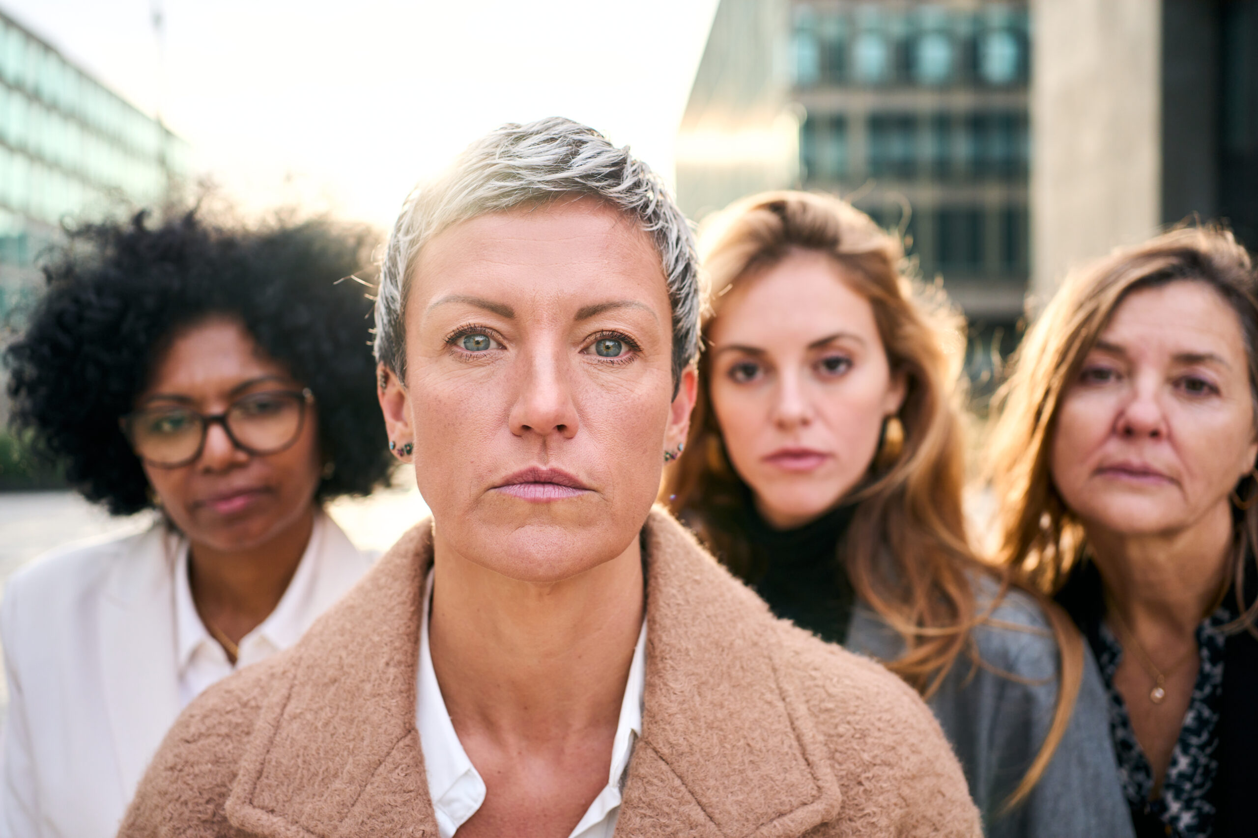 Portrait a group of multiracial serious business women of diverse ages looking at the camera with serious and relaxed expression. A Caucasian woman with short hair standing in foreground