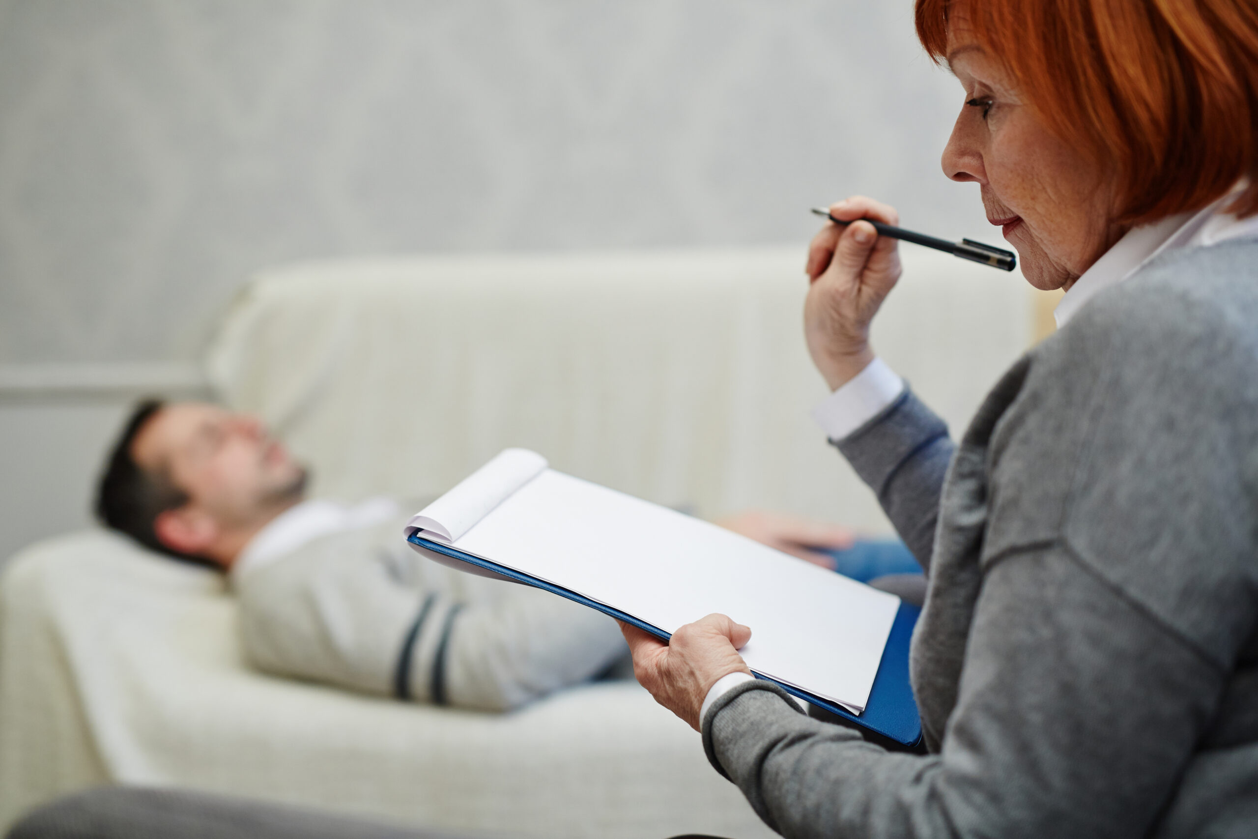 Pensive psychologist with blank paper listening to her anxious patient