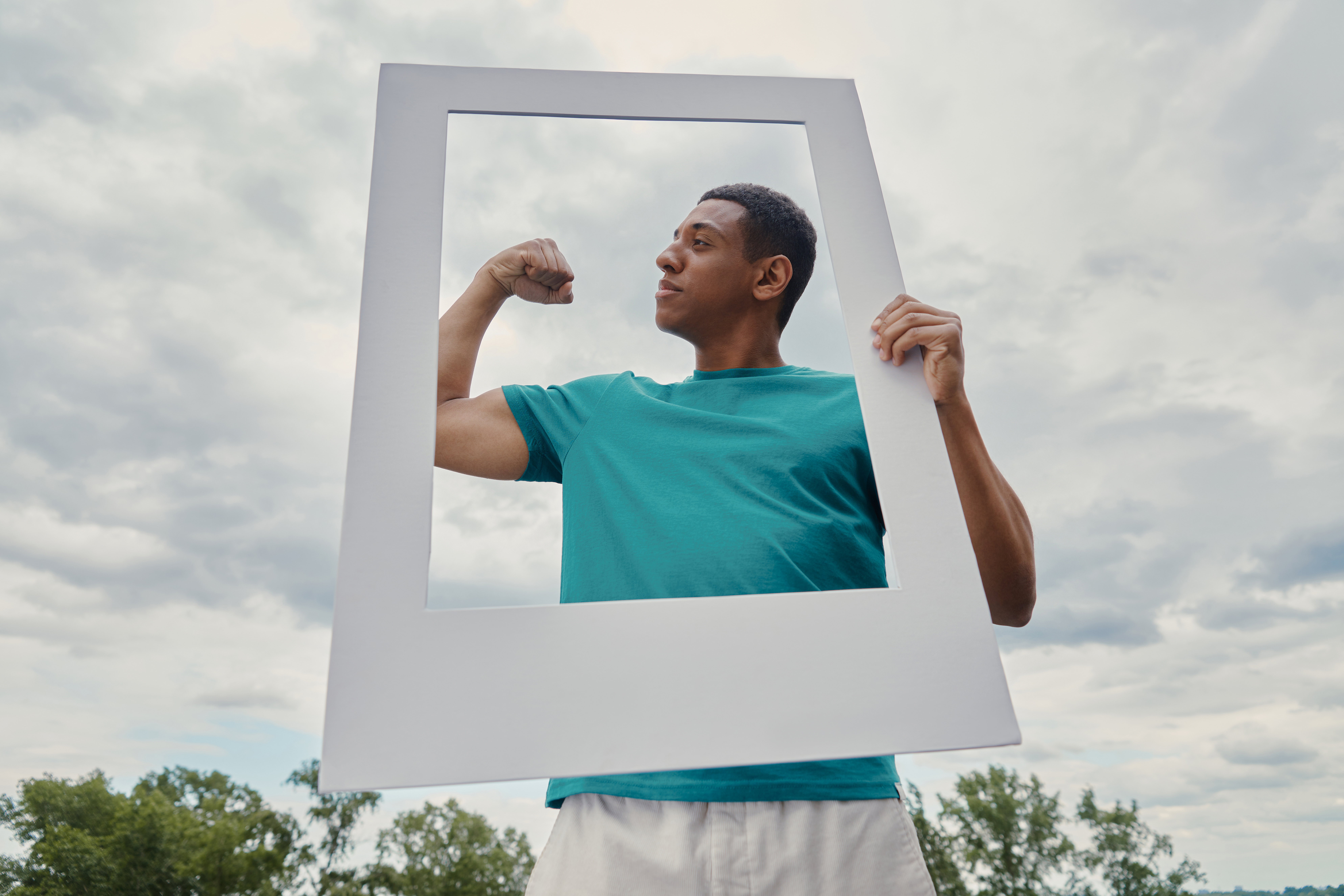 Confident mixed race man looking through a picture frame and gesturing while being outdoors
